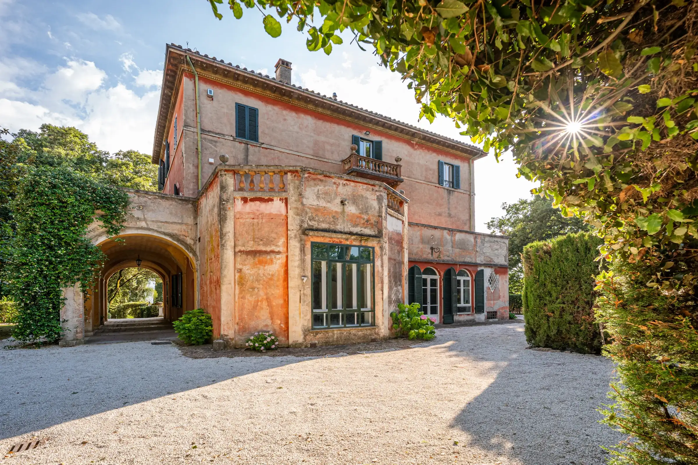 Side façade of the villa seen through a leafy arch